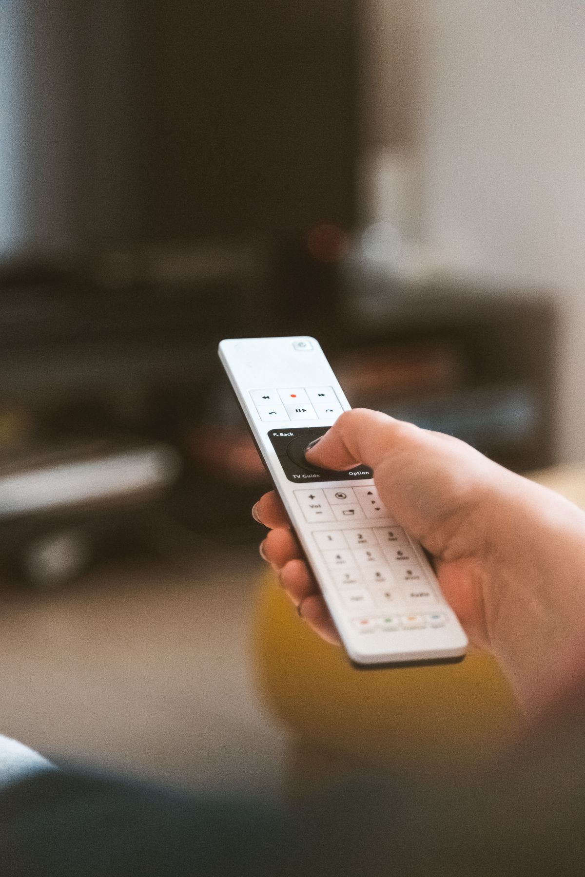 Pessoa usando controle remoto para navegar entre canais gratuitos na TV