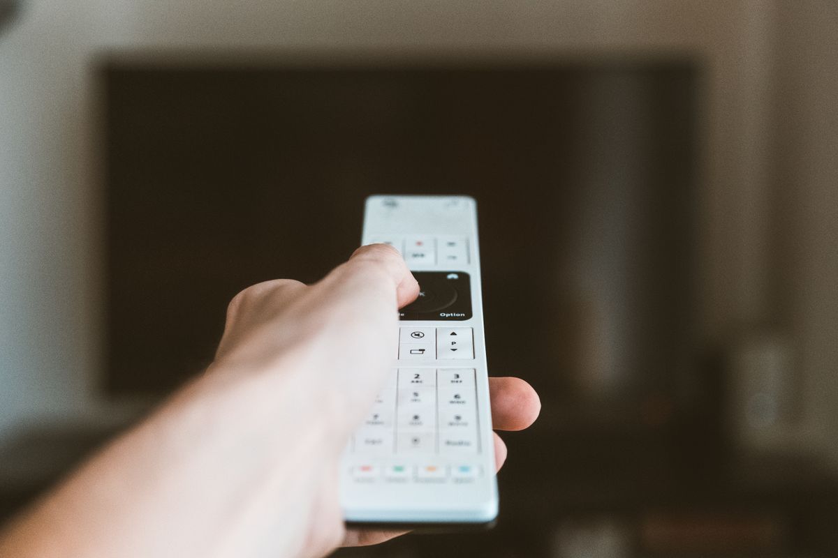 Mão segurando o controle remoto para navegar no sistema da Smart TV