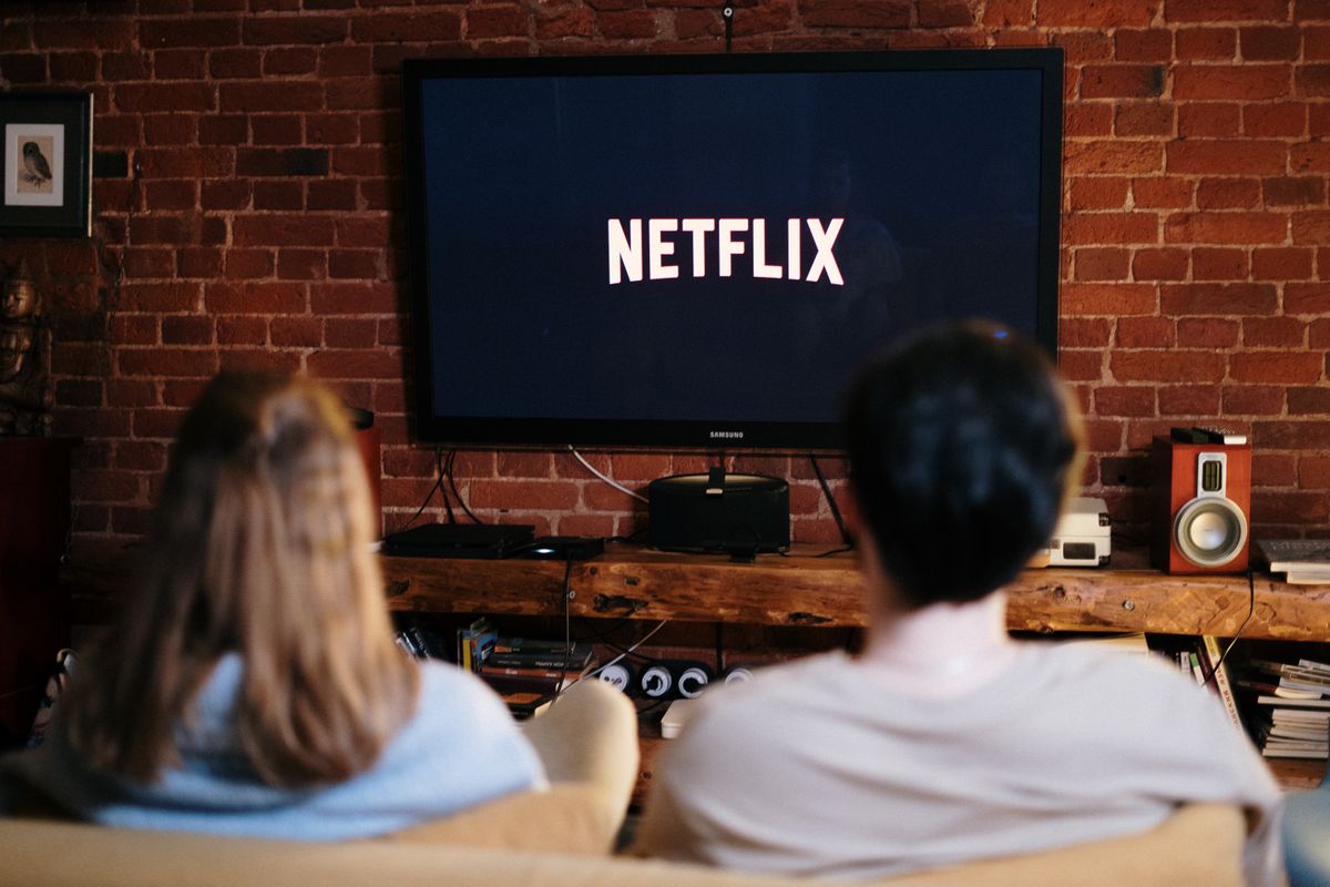 Casal assistindo a um serviço de streaming gratuito na TV da sala