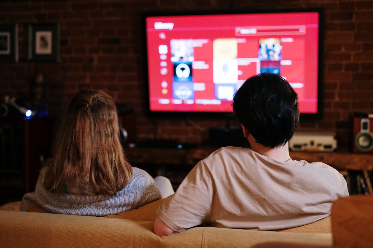Casal assistindo a conteúdo de streaming gratuito em uma TV grande
