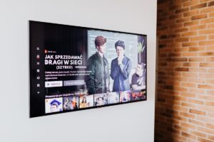 Smart TV preta na parede exibindo conteúdo de streaming em sala moderna