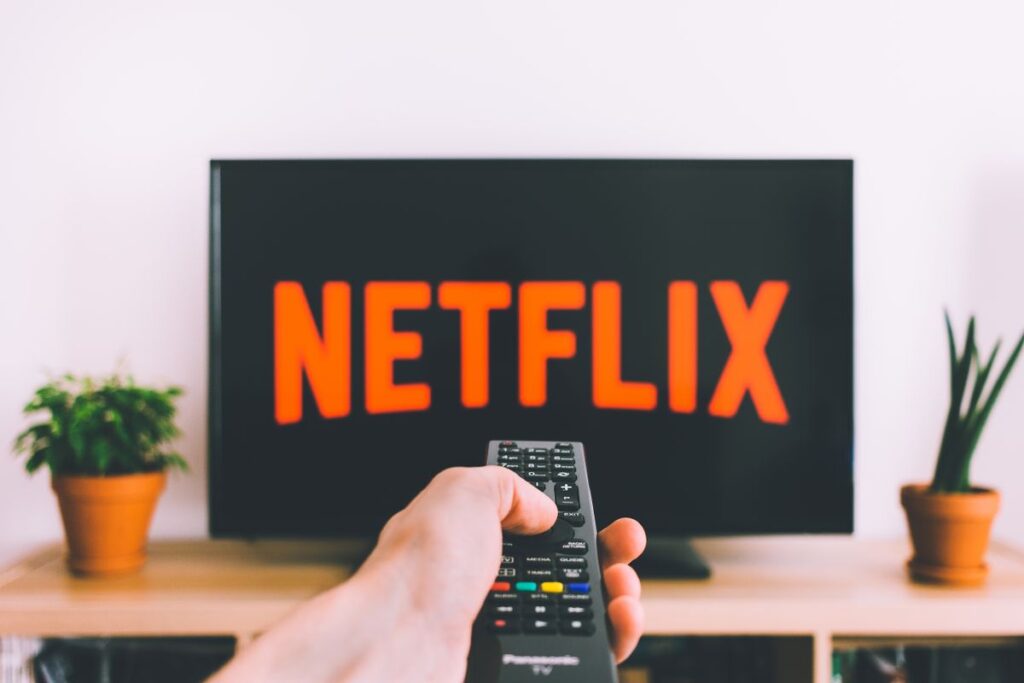 Pessoa segurando controle remoto apontado para TV com serviço de streaming